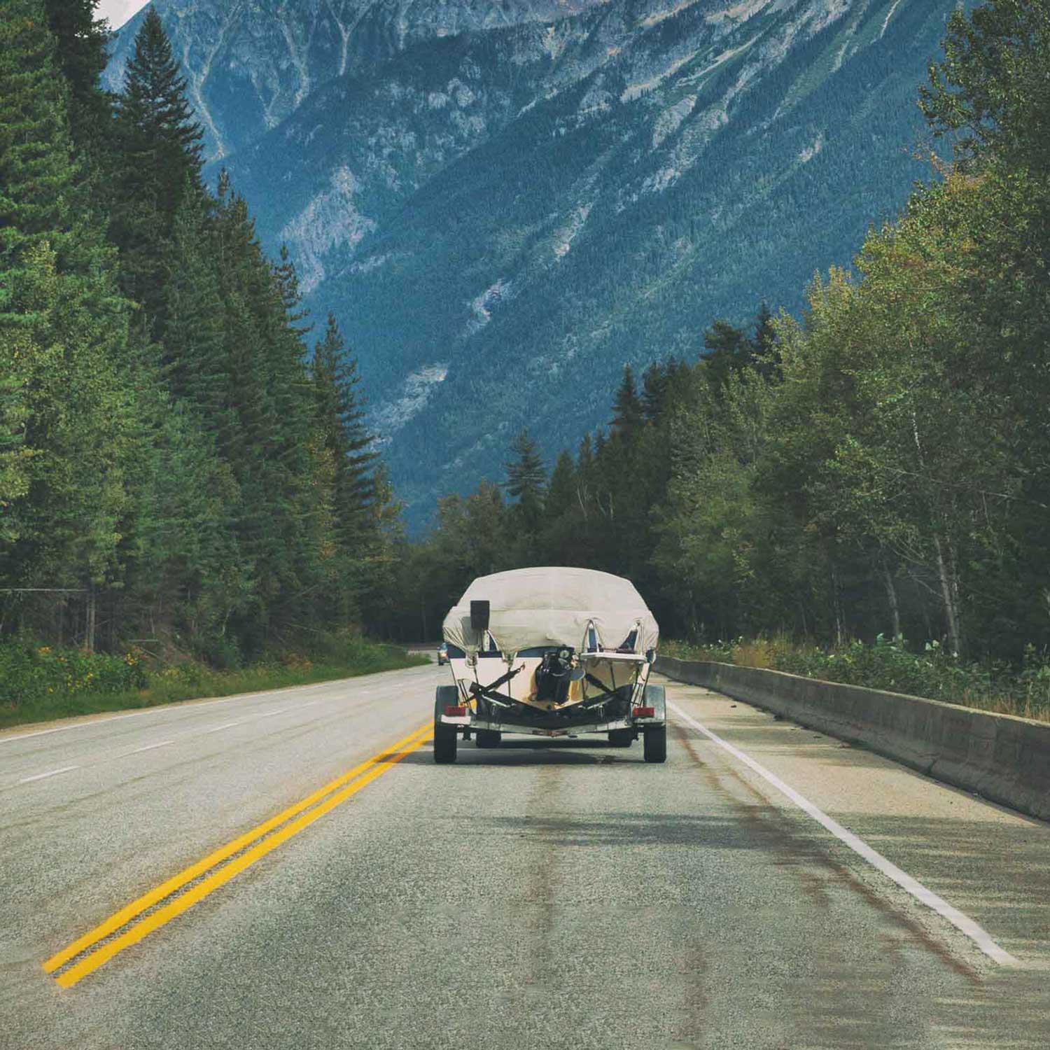 A boat trailer driving through the mountains.